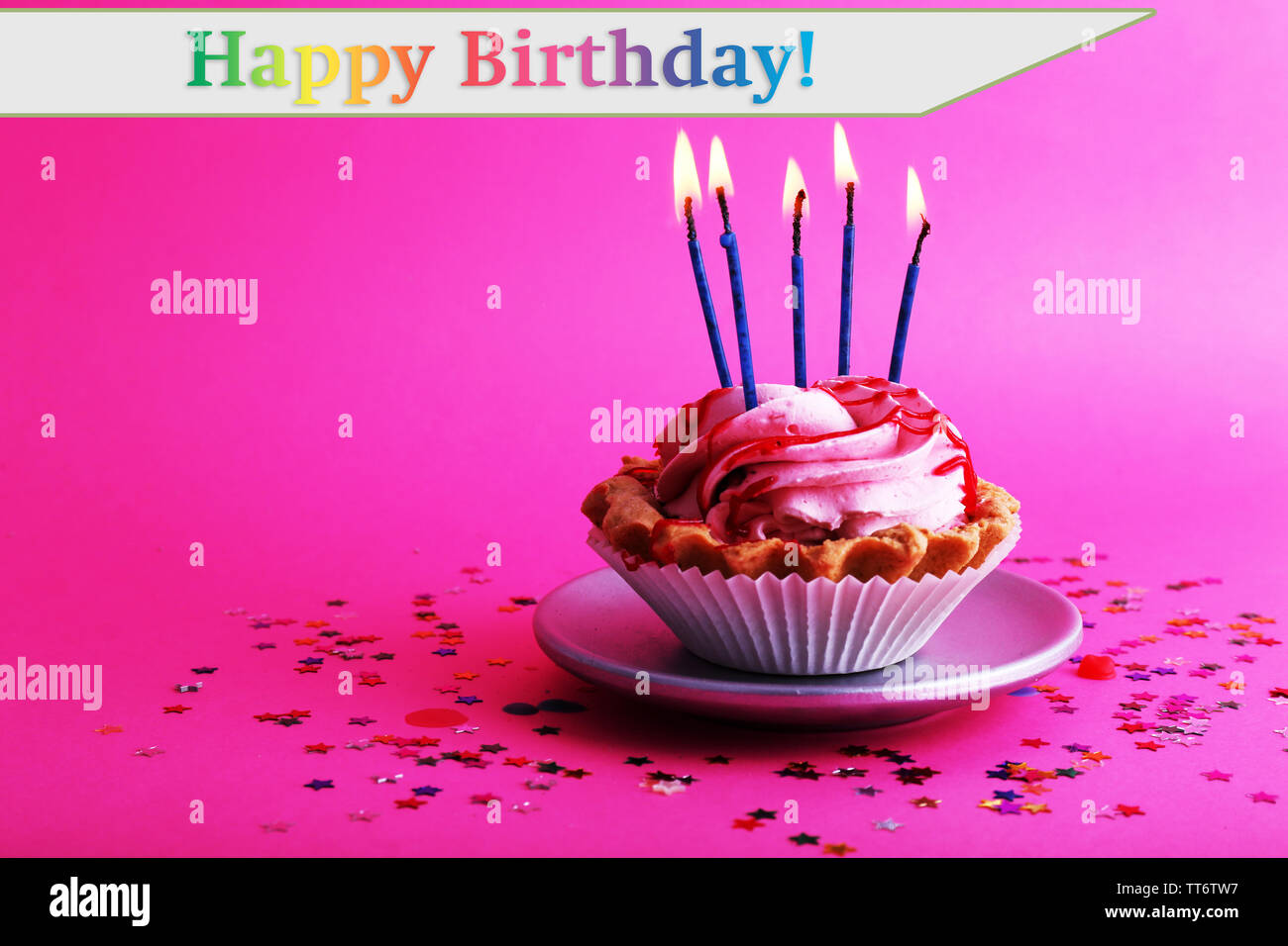 Birthday cup cake with candles and colorful stars on pink background ...