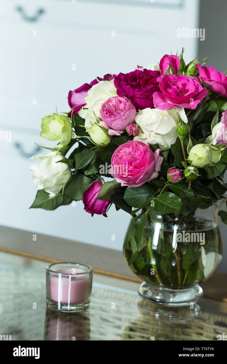 interior with fresh roses flowers and pink candle on the glass table Stock Photo