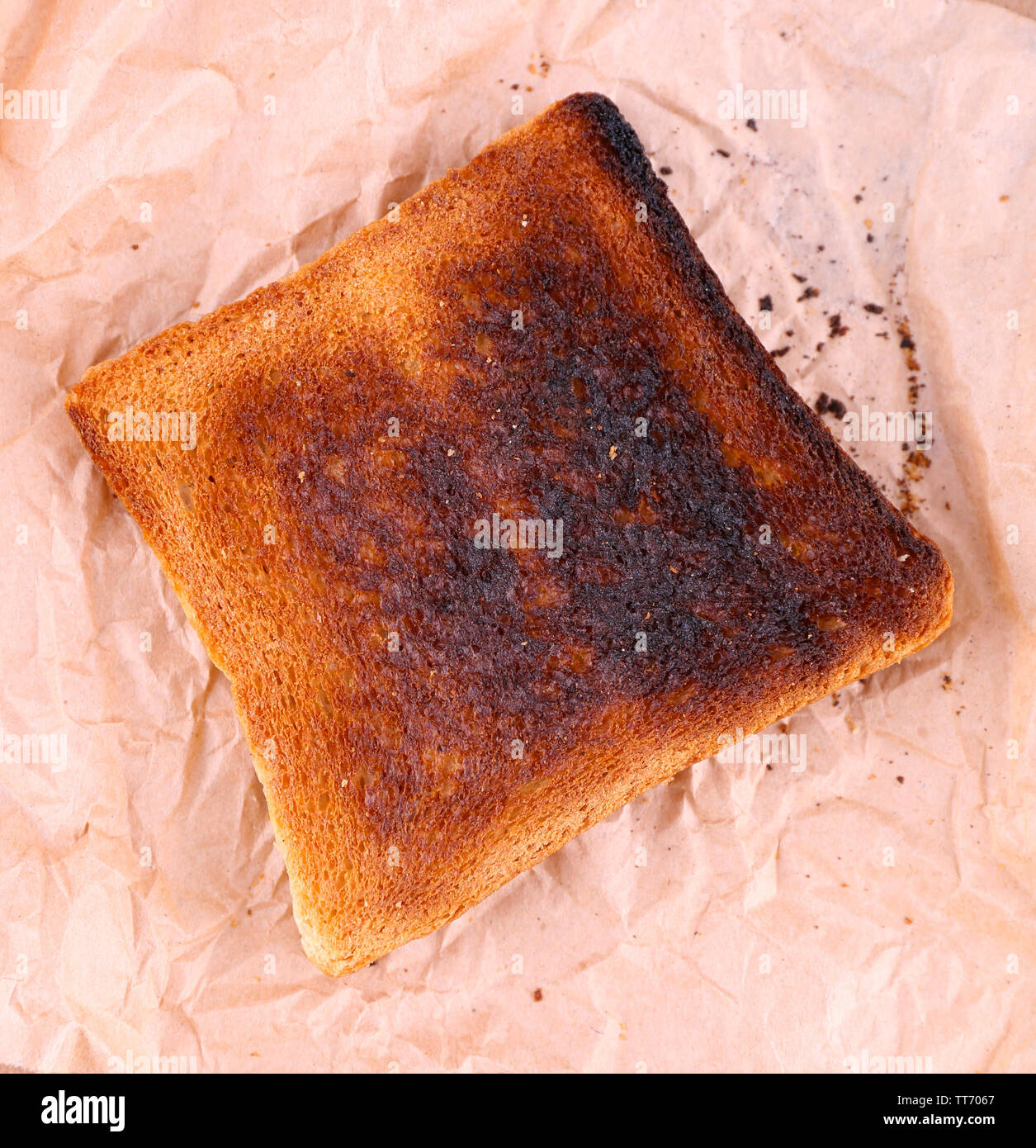 Burnt toasted bread on piece of paper and wooden table background Stock ...