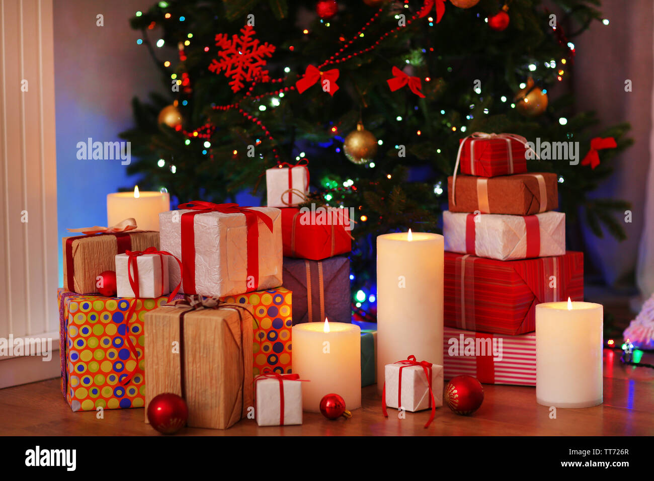 Pile of present boxes under Christmas tree on wooden floor, indoors