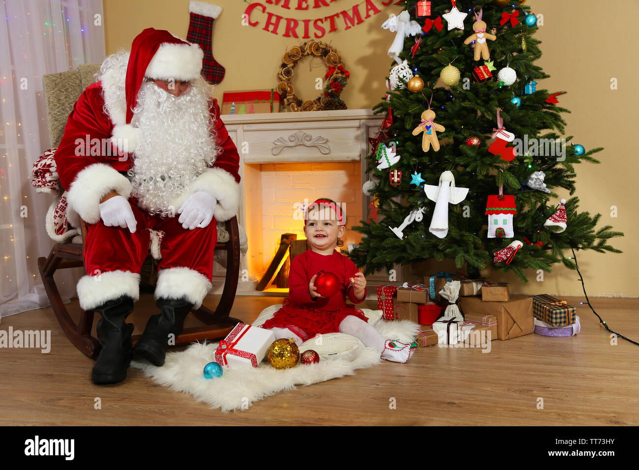Santa Claus giving present to little cute girl near fireplace and ...