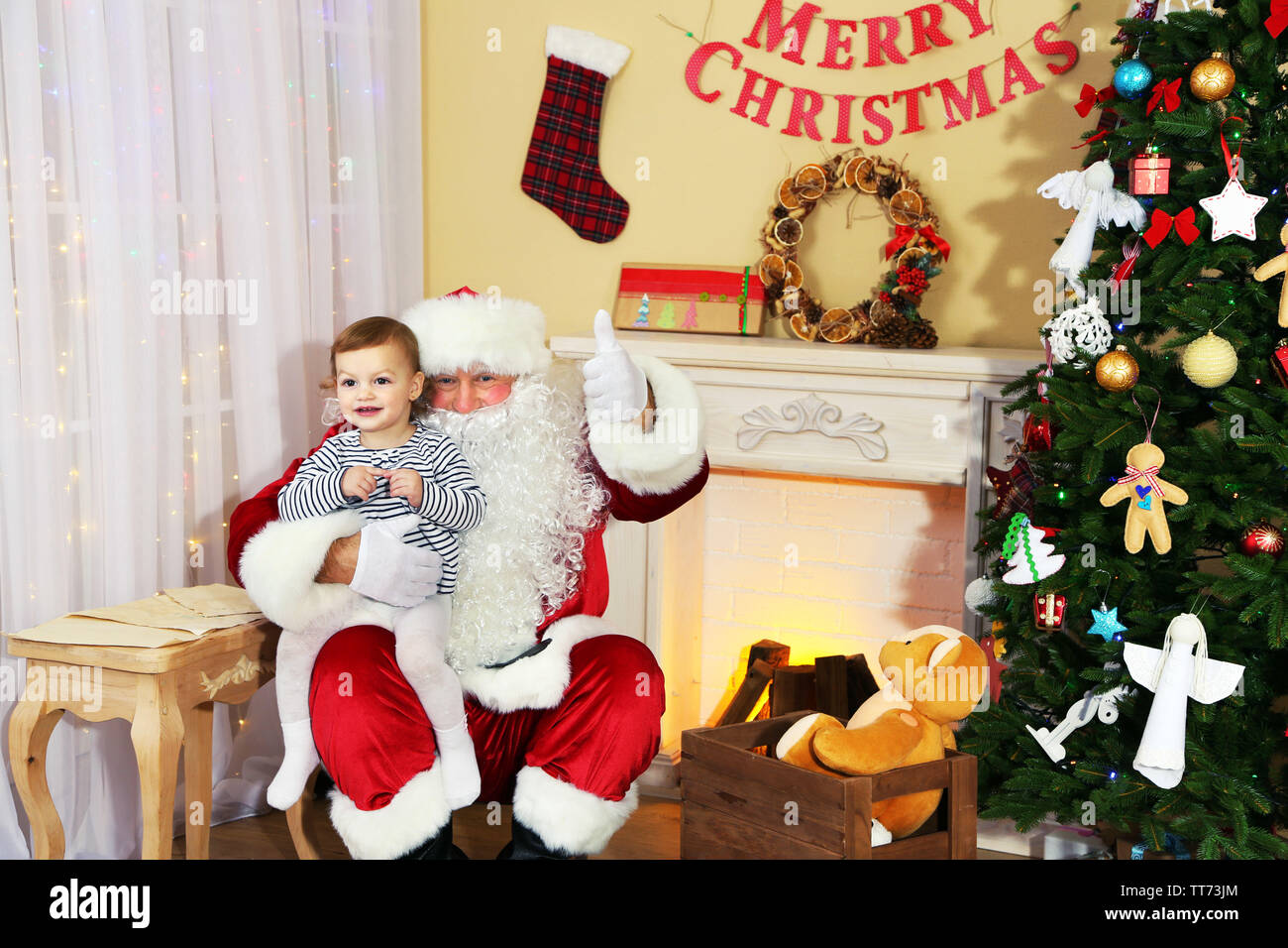 Santa Claus giving present to little cute girl near fireplace and ...