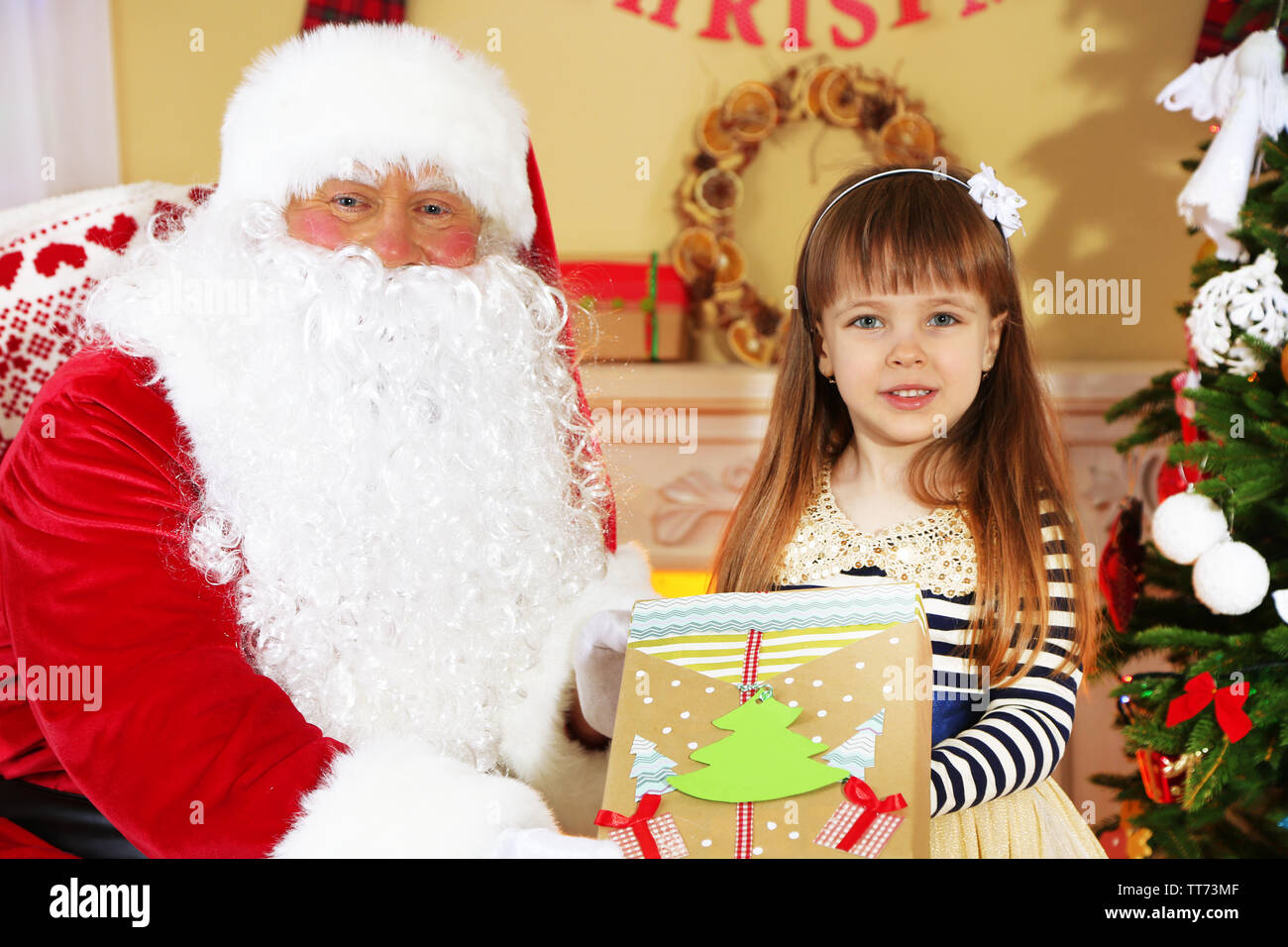Santa Claus giving present to little cute girl near Christmas tree at ...