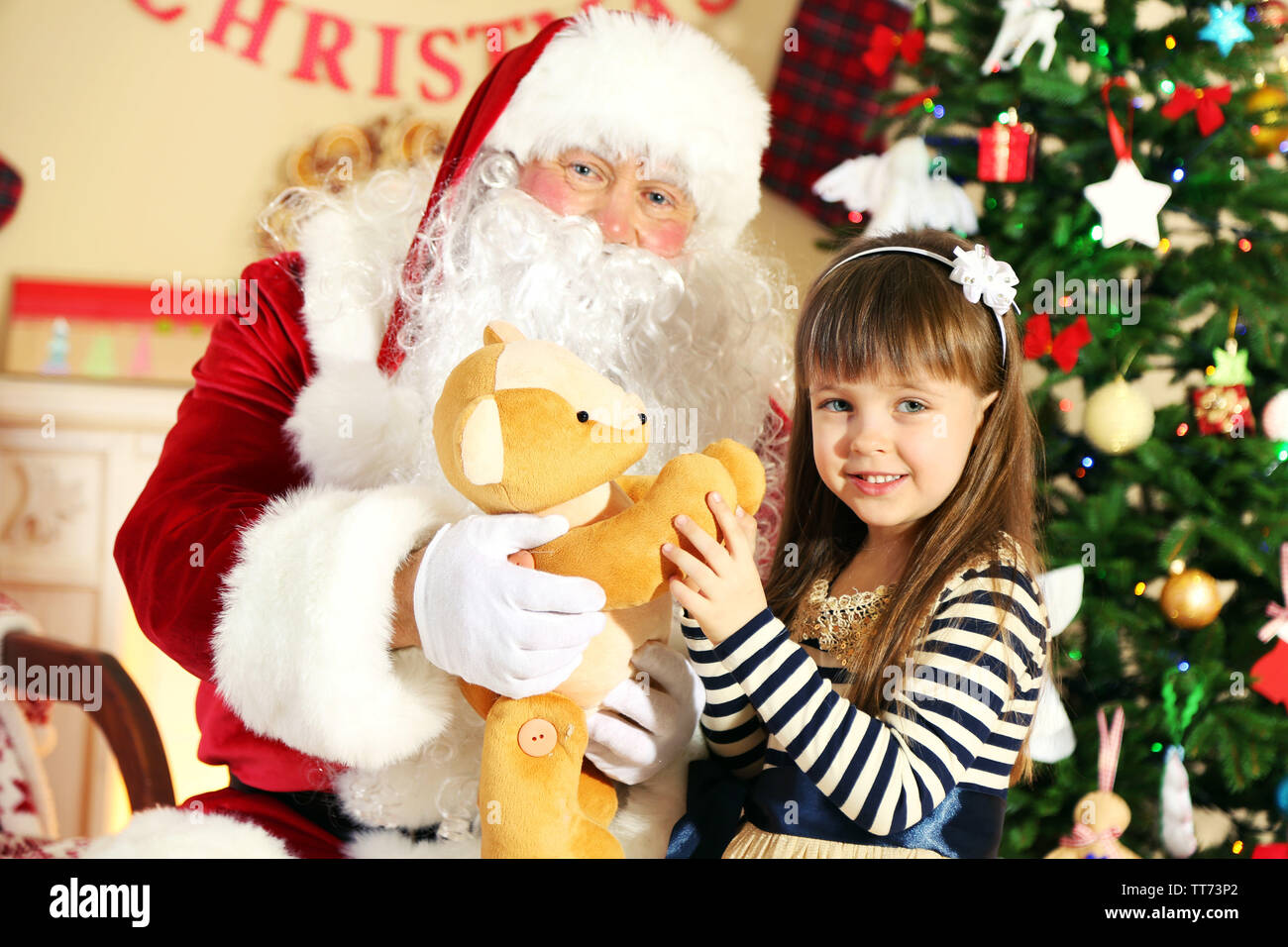 Santa Claus giving present to little cute girl near Christmas tree at ...