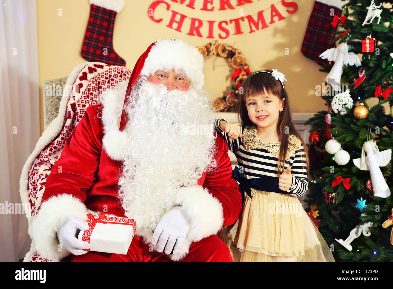Santa Claus giving present to little cute girl near Christmas tree at ...