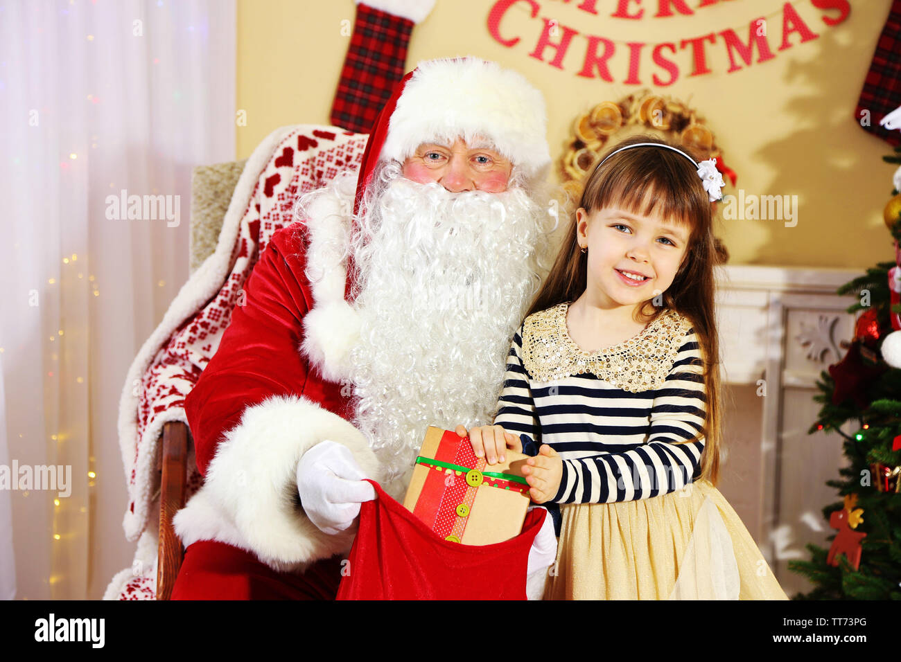Santa Claus giving present to little cute girl near Christmas tree at ...