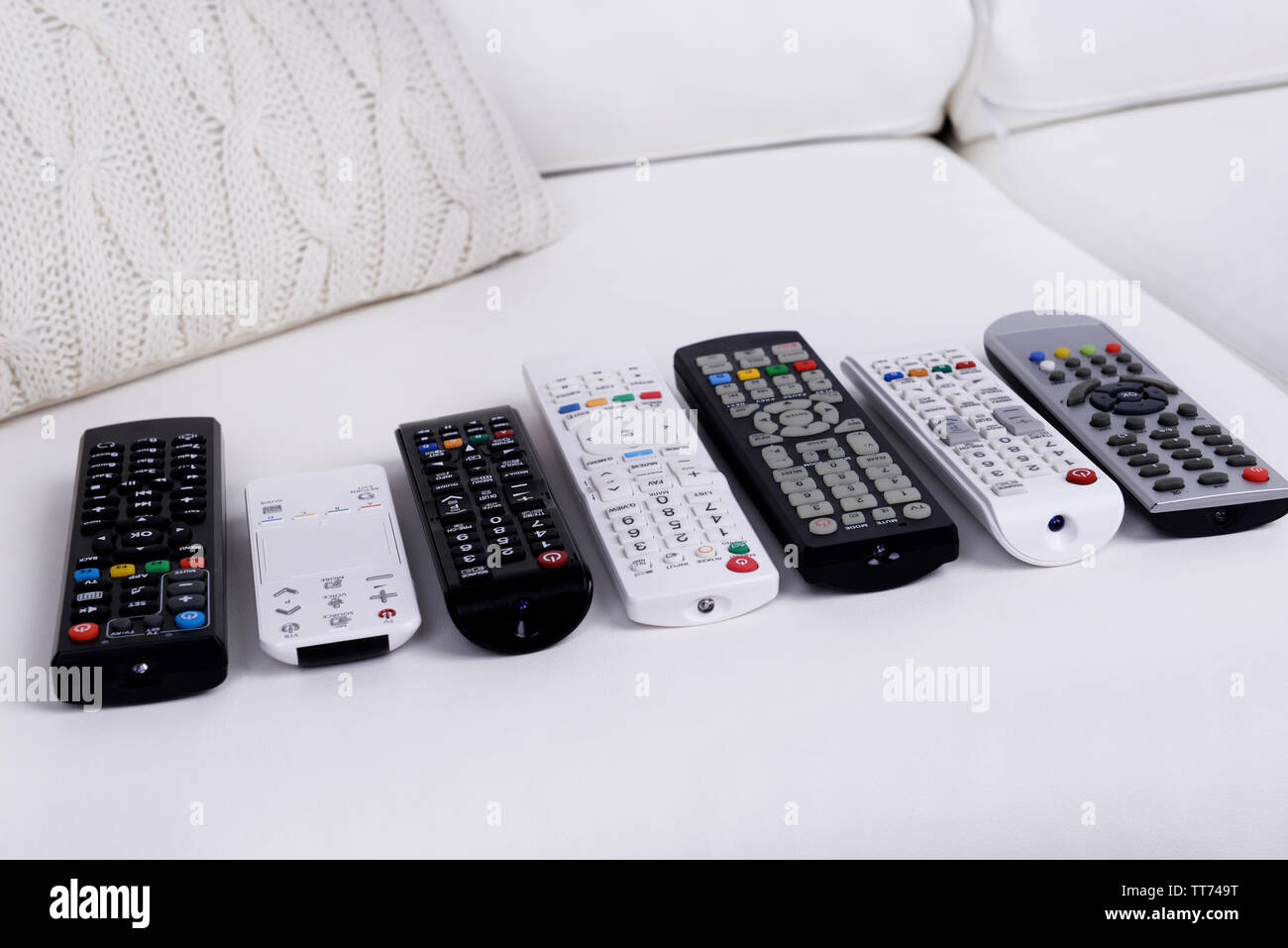 Many remote control devices on sofa Stock Photo