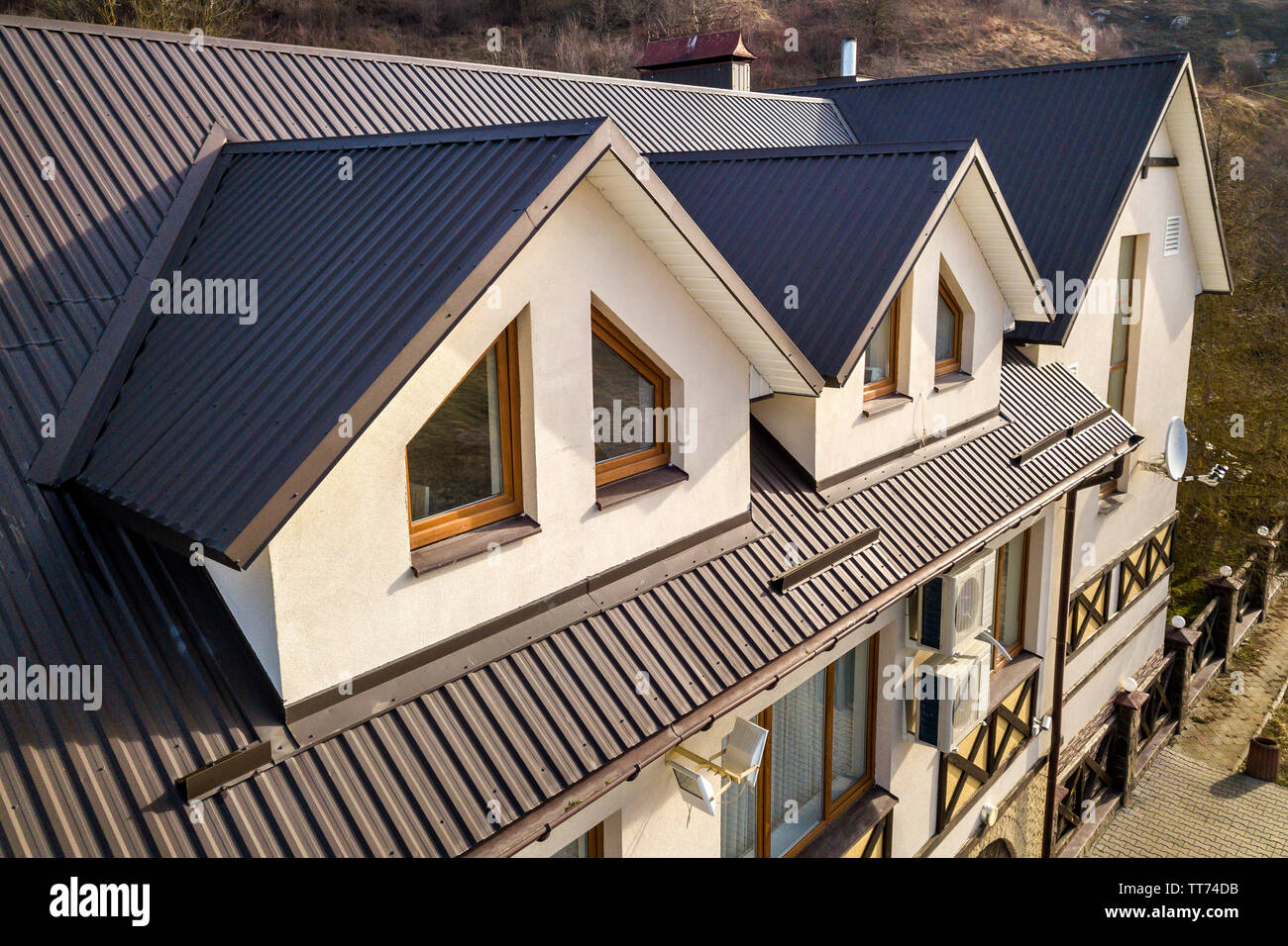 Close-up aerial view of building attic rooms exterior on metal shingle ...