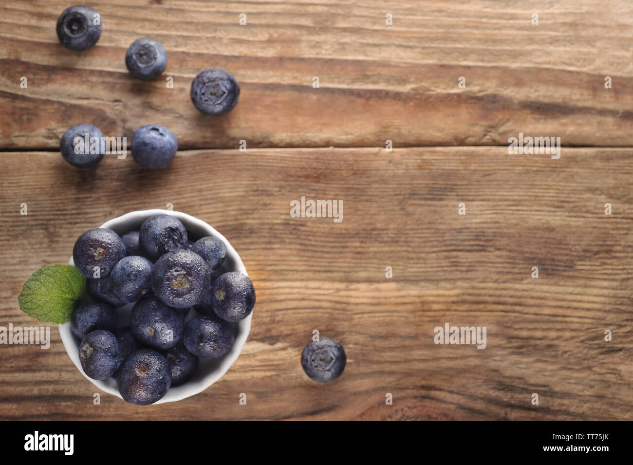 Small bowl of blueberries on wooden table. Concept for farming, agriculture, healthy diet, freshness, organic foods. Flat lay with copy space. Stock Photo