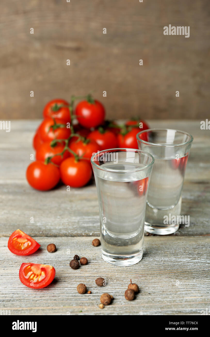 Glasses of ouzo and tomatoes on wooden table Stock Photo