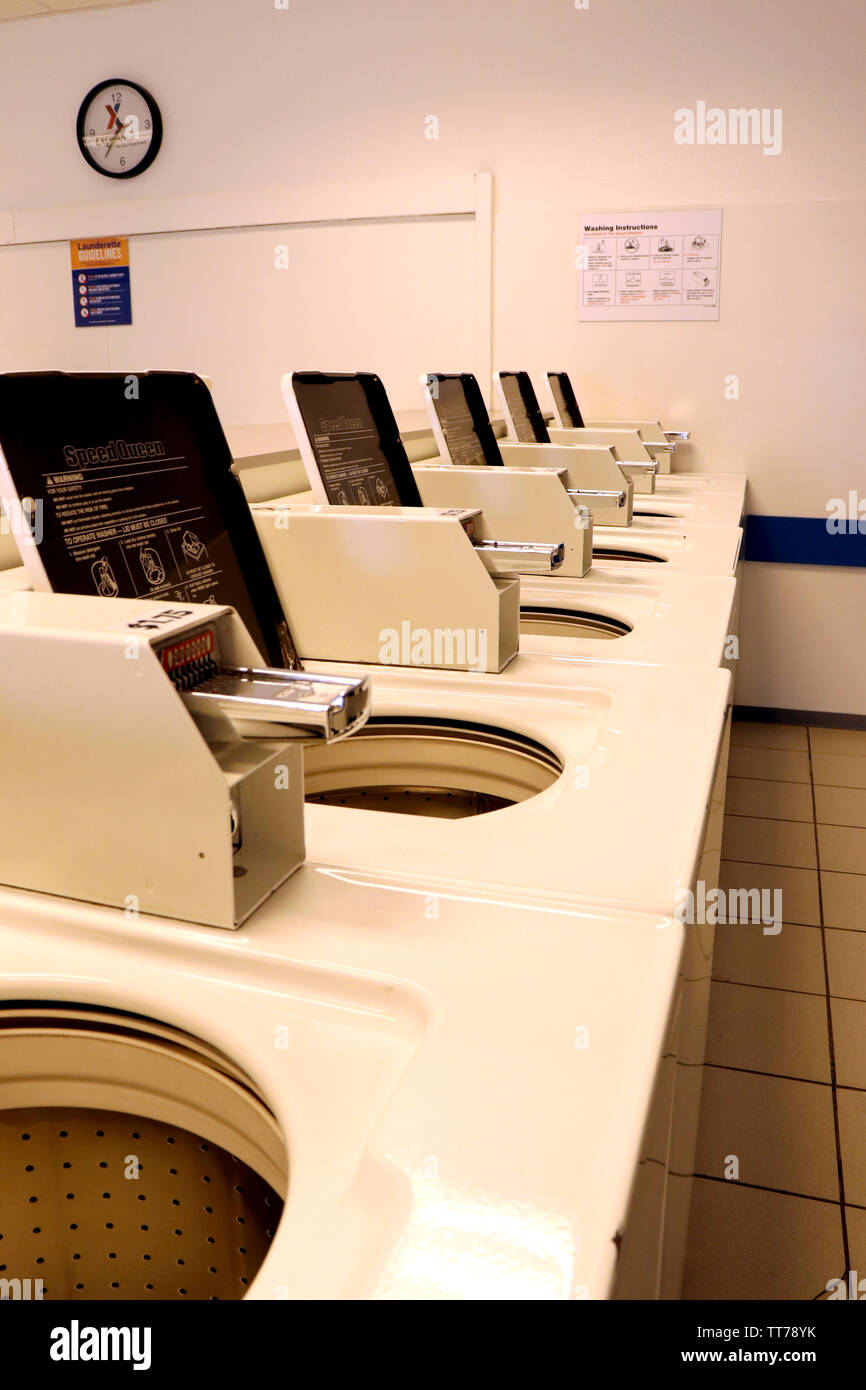 A row of empty washing machines with lids open in a laundromat. Stock Photo