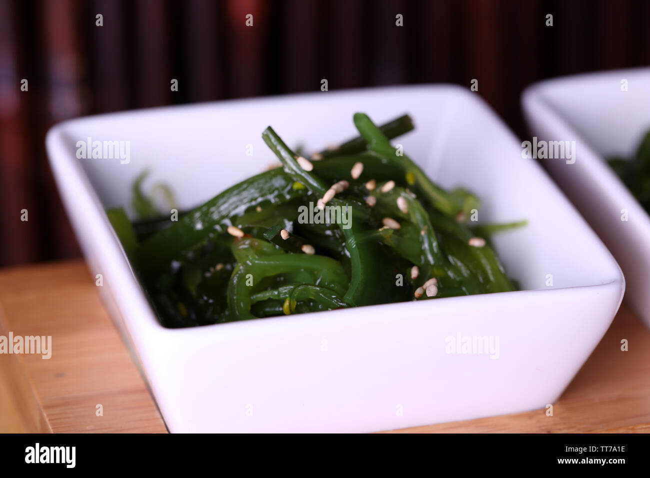 Seaweed salad with cherry tomatoes on wooden stand and bamboo on background Stock Photo