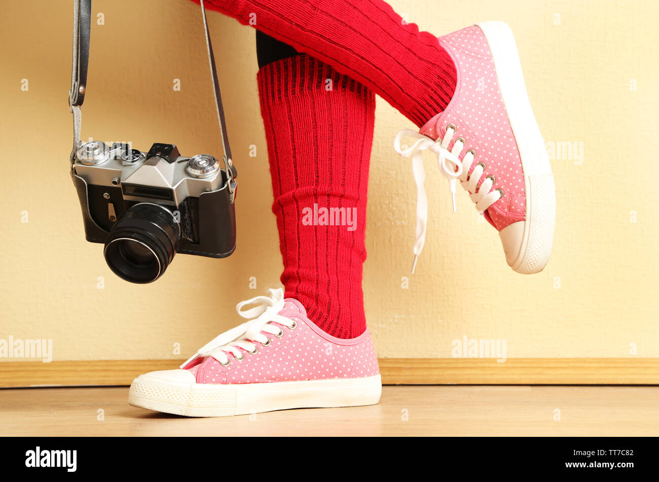 Girl in sneakers with retro photo camera in room Stock Photo - Alamy