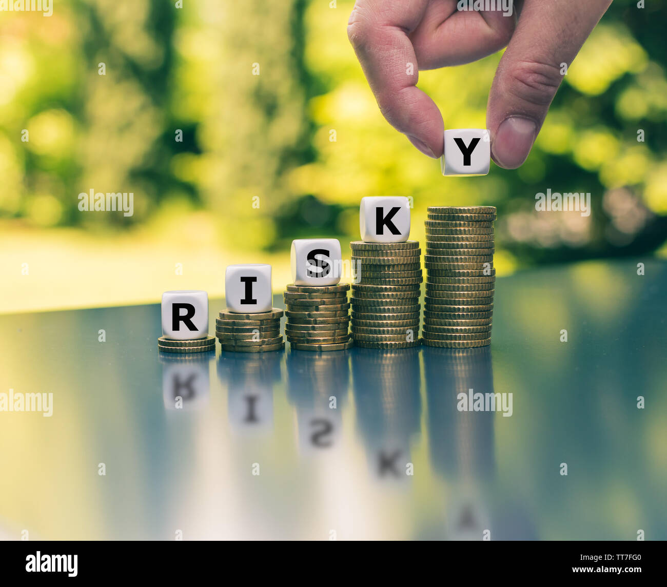 Concept of a increasing high financial risk. Dice placed on increasing high stacks of coins form the word 'risky'. Stock Photo