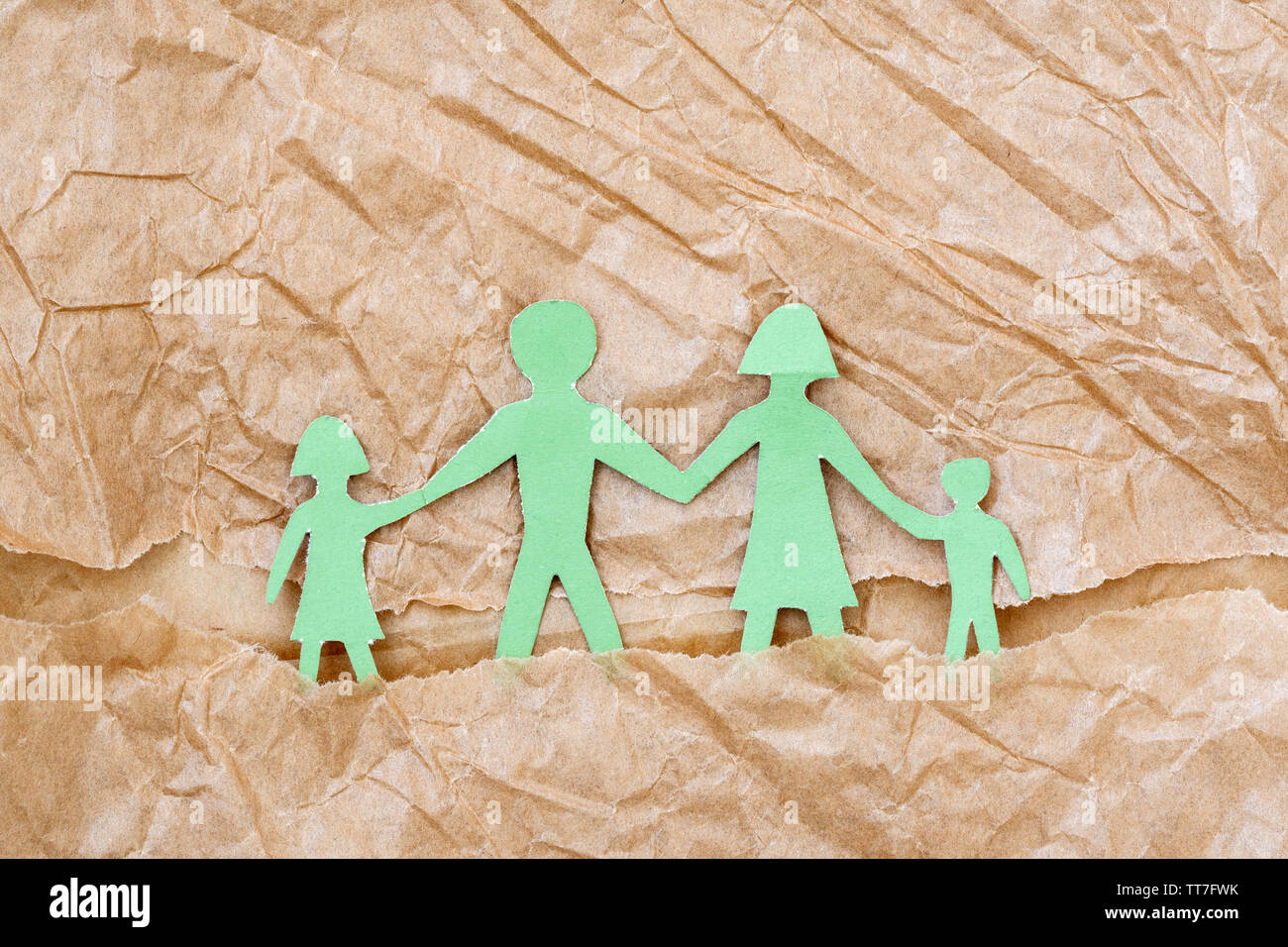 Family with two children, paper figures on a brown paper background ...