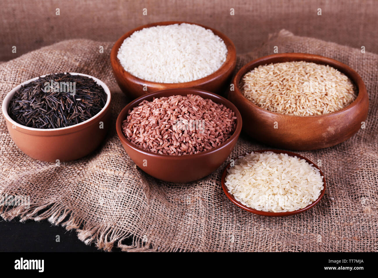 Different Kinds Of Rice In Bowls On Sackcloth Background Stock Photo Different kinds of rice in bowls on sackcloth background stock photo