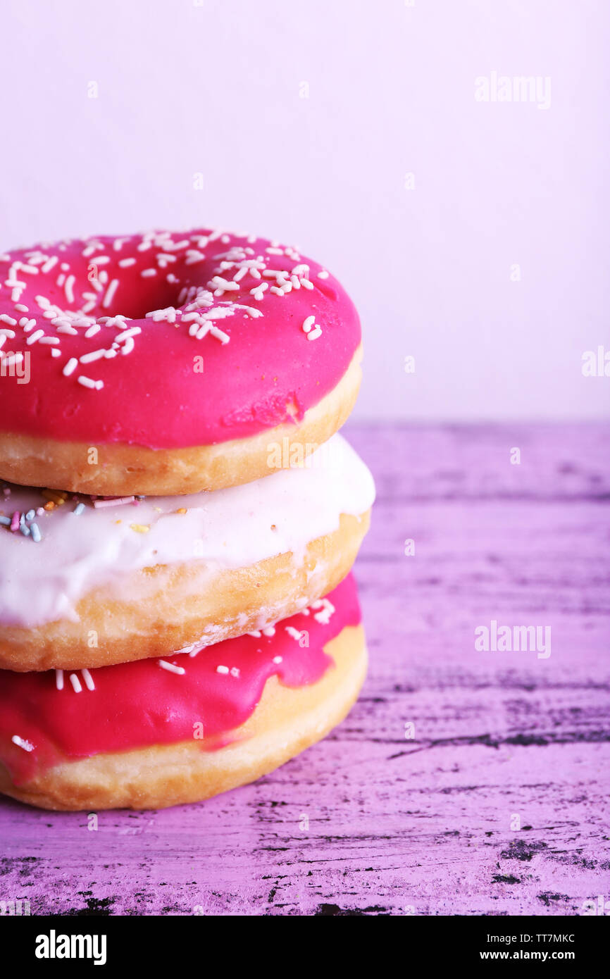 Delicious donuts with icing on table on light background Stock Photo