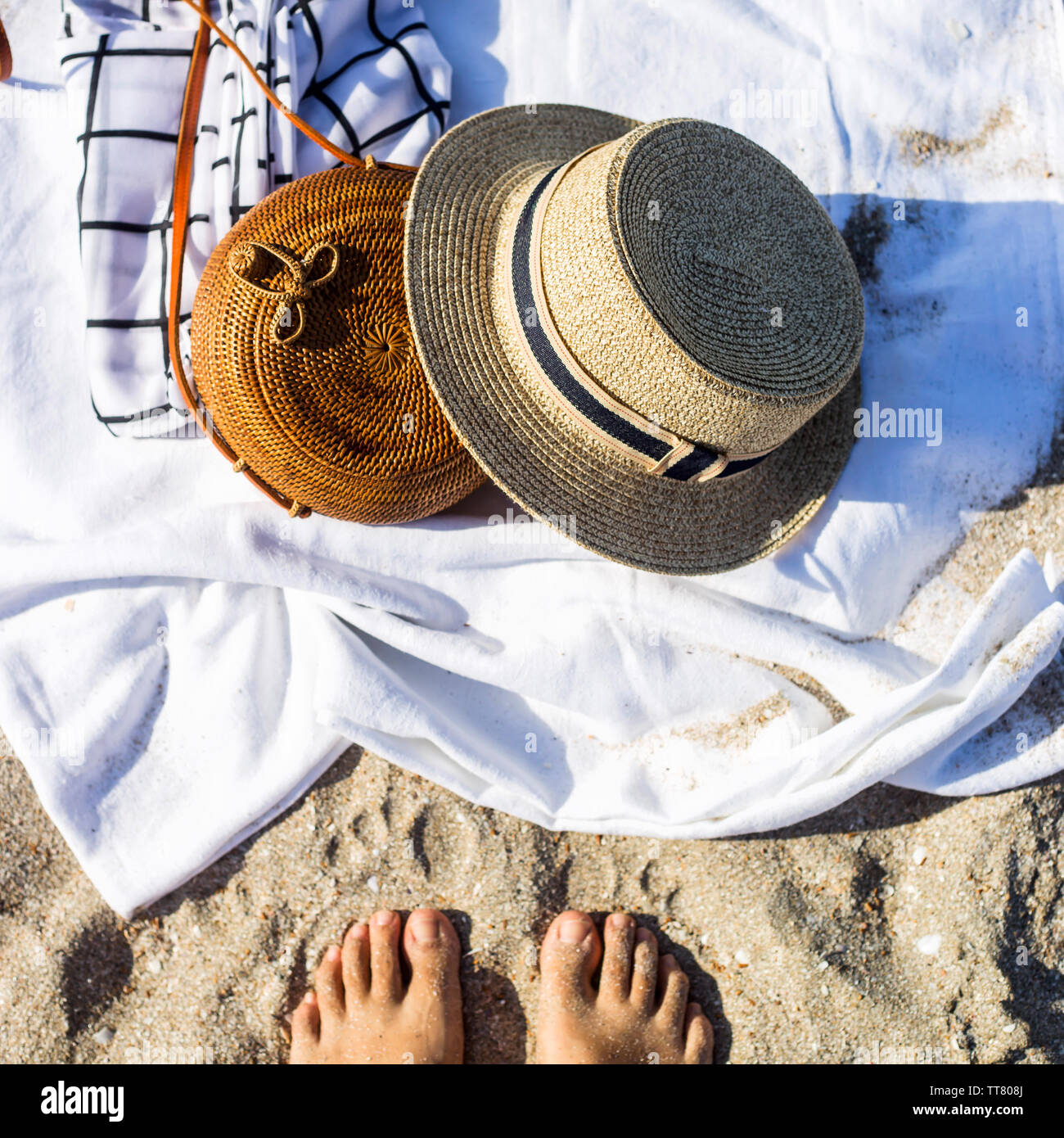 Straw hat and bag on a white bed which lies on the sand on the beach ...