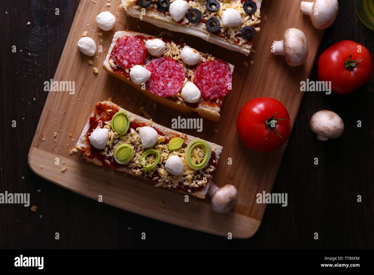 Different sandwiches with vegetables and cheese on cutting board on