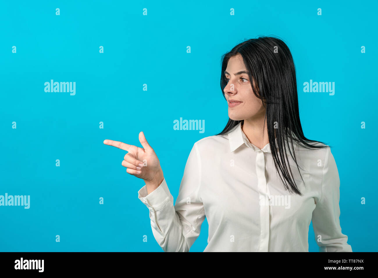Happy bussiness girl with blue background, showing her finger up and smiling. startup girl looks away and shows her finger on copyspace. Isolated on a Stock Photo
