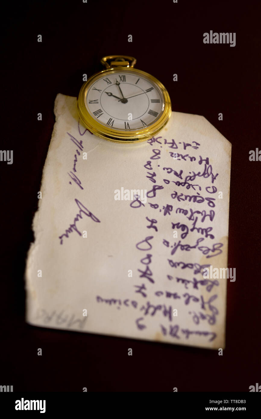 ancient yellowed handwritten note with near a pocket clock Stock Photo
