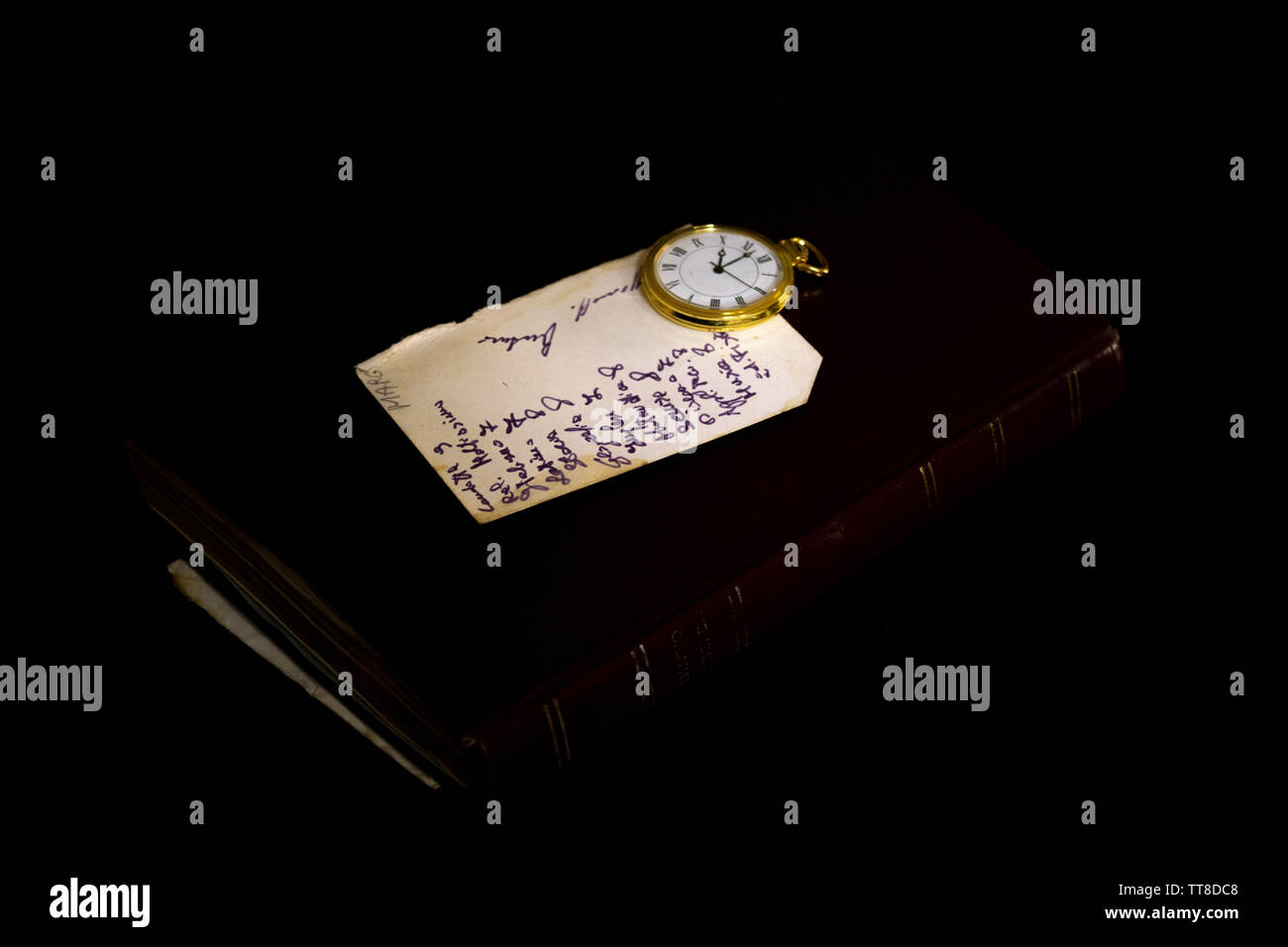 ancient yellowed handwritten note with near a pocket clock Stock Photo