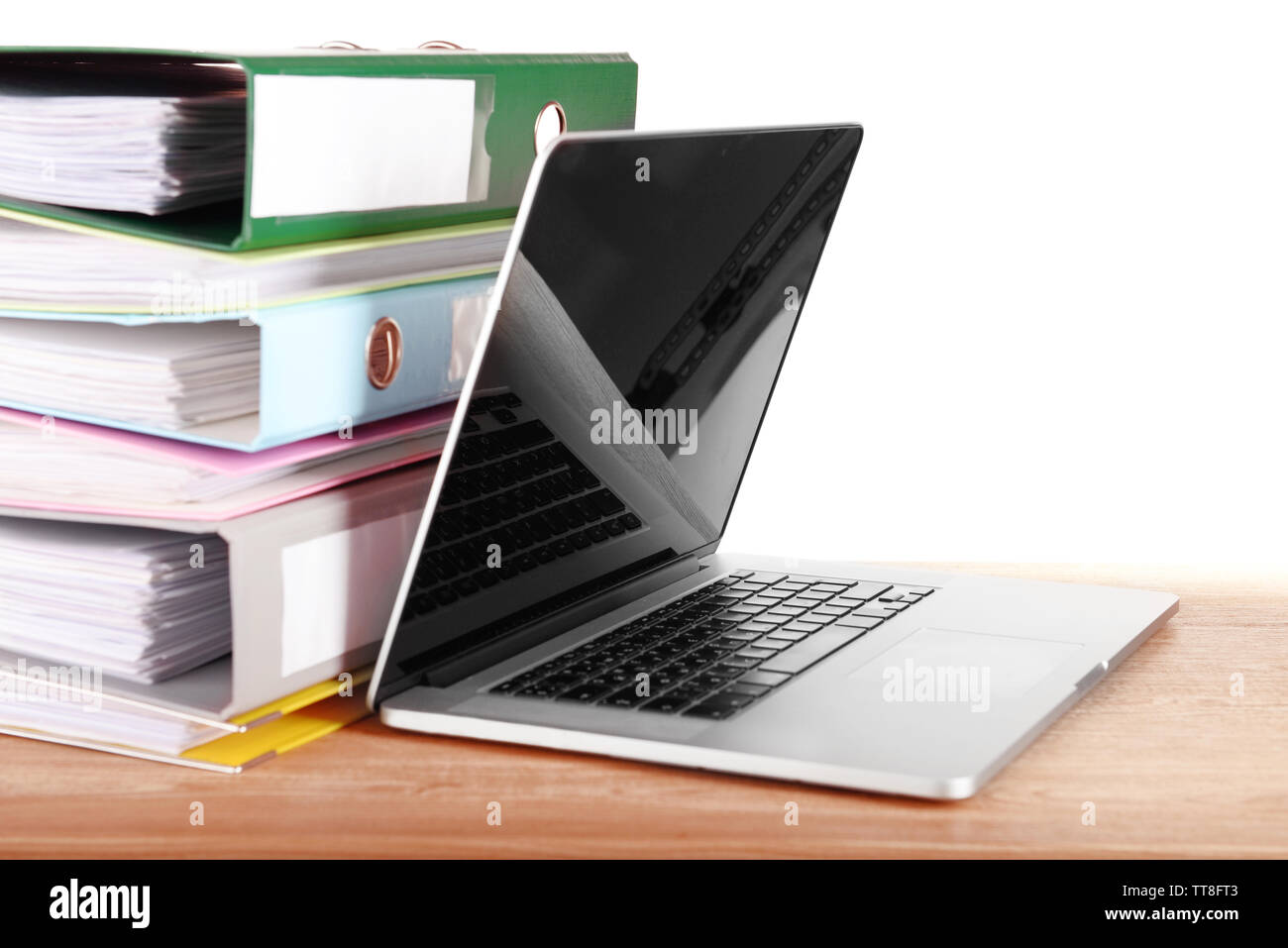 Laptop with stack of folders on table on white background Stock Photo