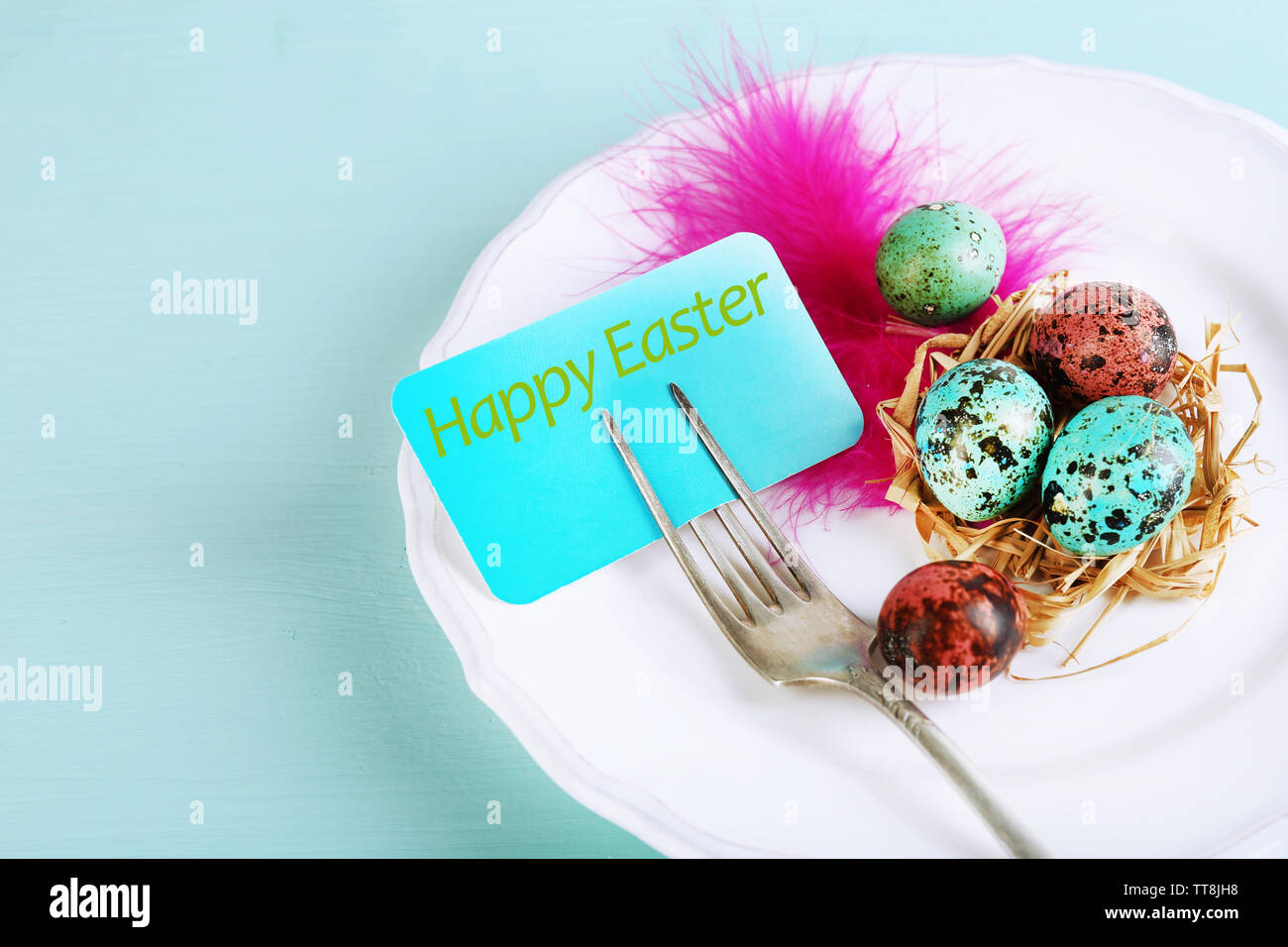 Easter table setting with card and Easter eggs on wooden background Stock Photo
