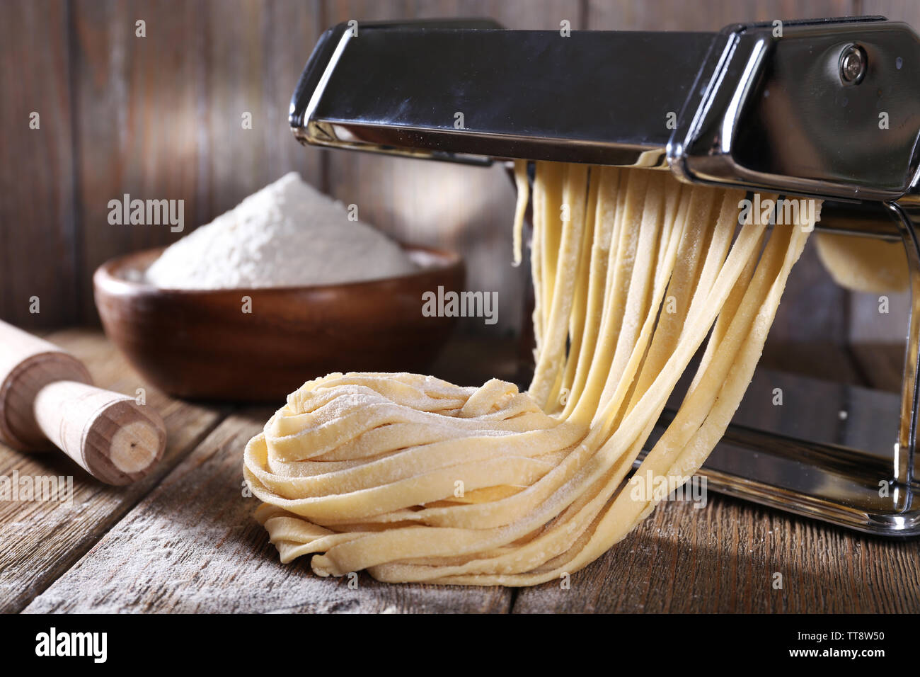https://c8.alamy.com/comp/TT8W50/making-noodles-with-pasta-machine-on-wooden-background-TT8W50.jpg
