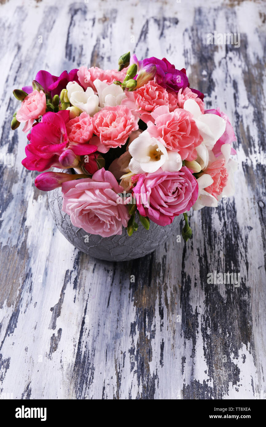 Beautiful fresh spring flowers in pot on wooden table, closeup Stock Photo