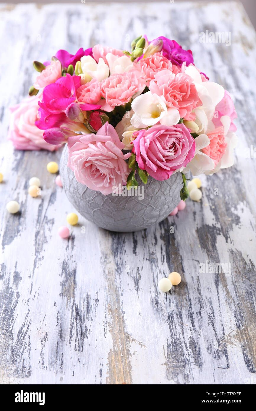 Beautiful fresh spring flowers in pot on wooden table, closeup Stock Photo