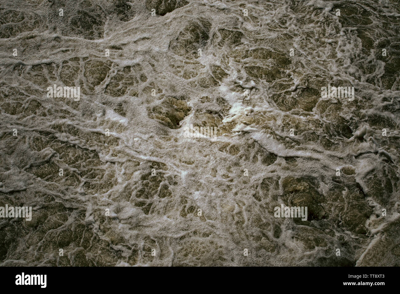 Abstract background, rough water surface. Foaming water, darkness. Foam and bubbles. Stormy waves. Splendor, magnificence and power of nature concept. Stock Photo