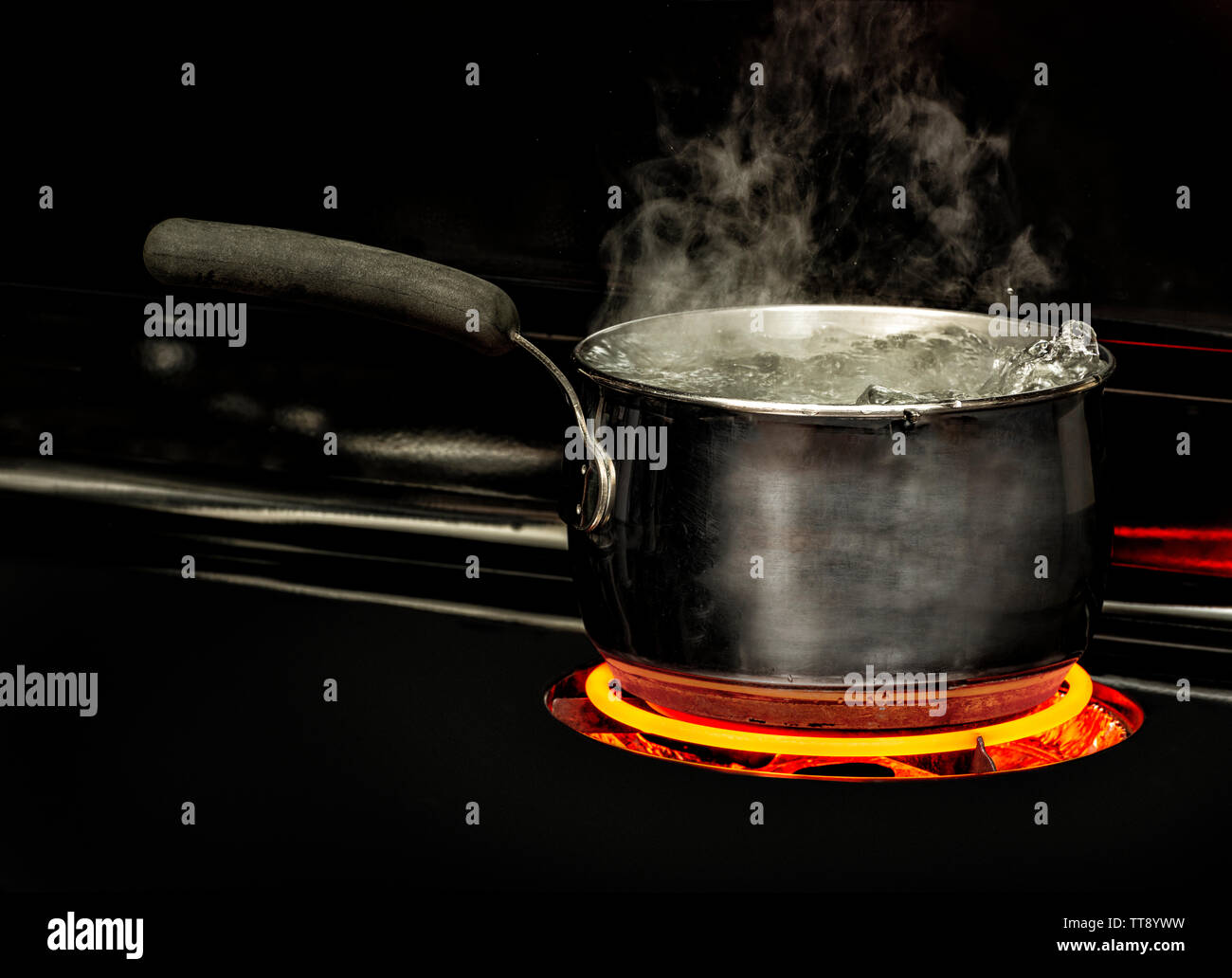 Horizontal shot of a boiling pot of water on a stovetop with a glowing red element. Stock Photo