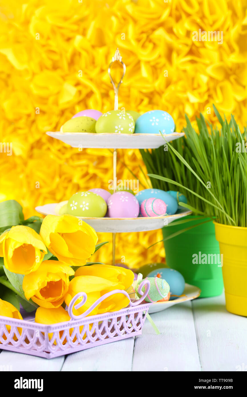 Easter eggs on vase and tulips on table on yellow background Stock ...