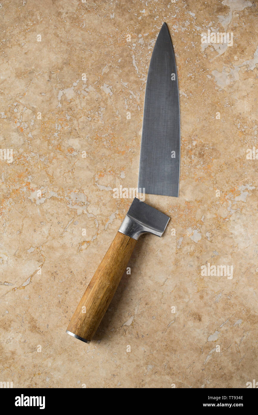 A broken kitchen knife displayed on a light stone background. England