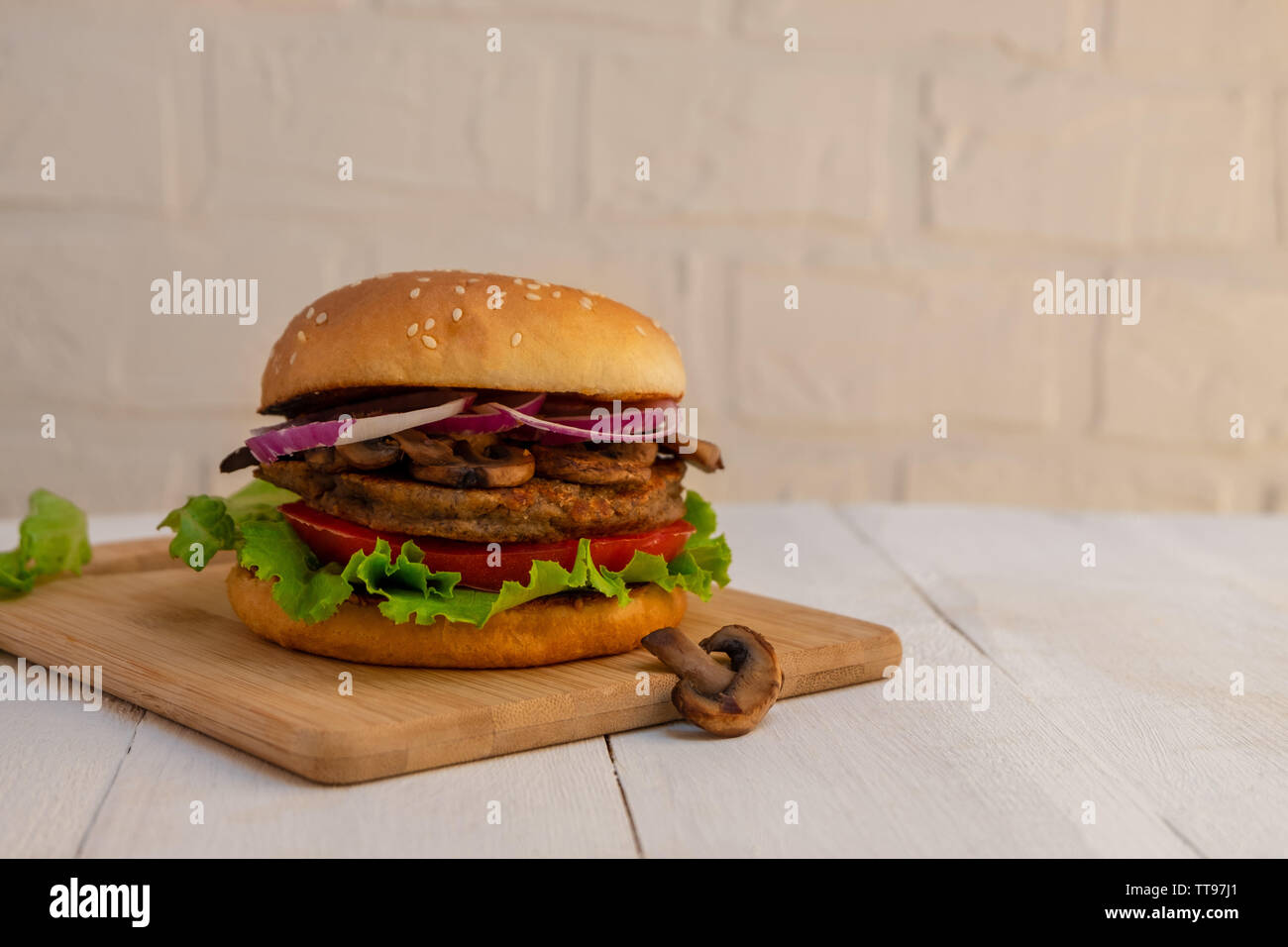Homemade mushroom veggie burger on white wooden background with copy
