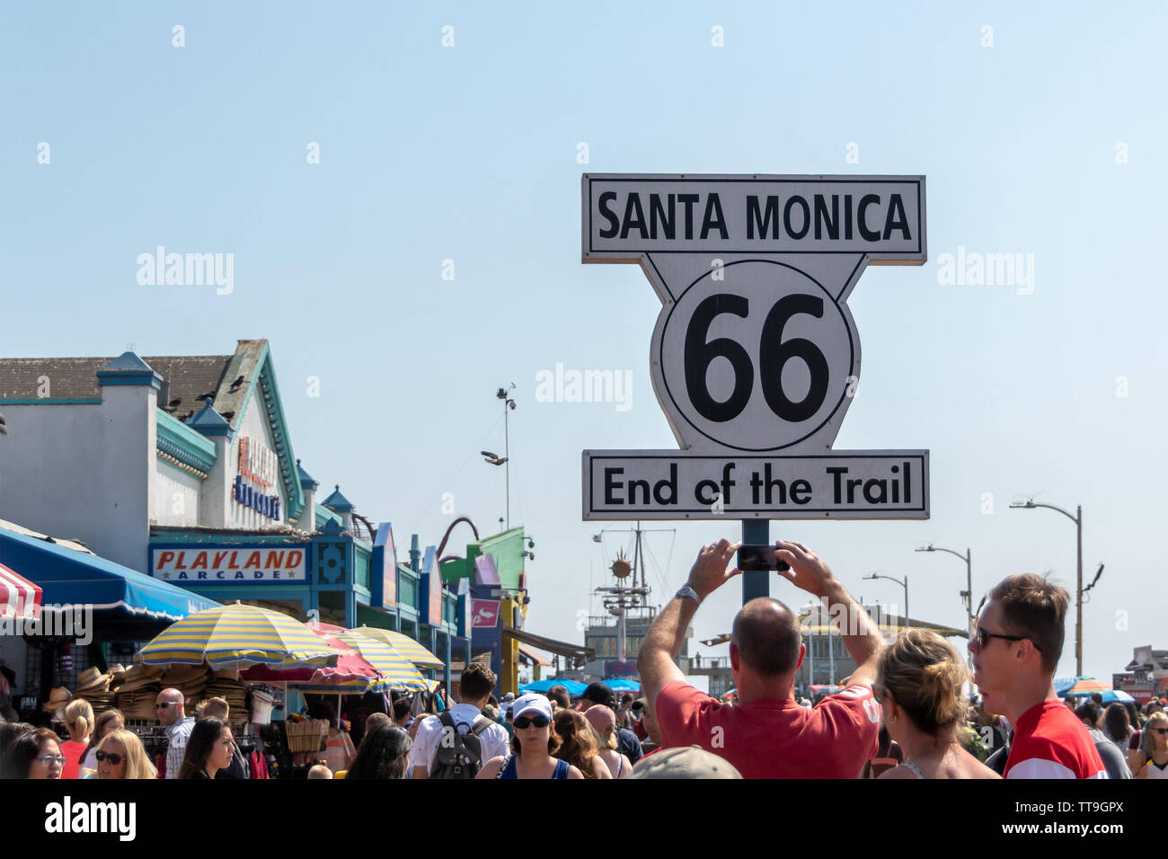 Santa Monica, CA, USA - July 27, 2018 - Tourists taking pictures of a sign that marks the end of the Route 66 on the pier in Santa Monica, CA, USA, on Stock Photo