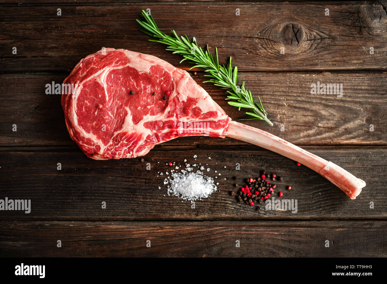 raw Tomahawk steak on wooden background with spices for grilling Stock Photo