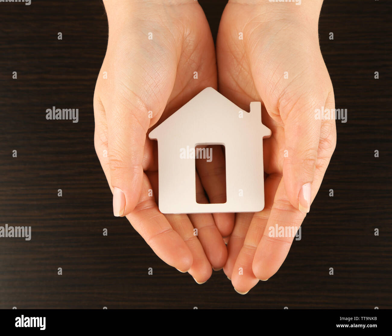 Female hands with model of house on wooden table background Stock Photo ...