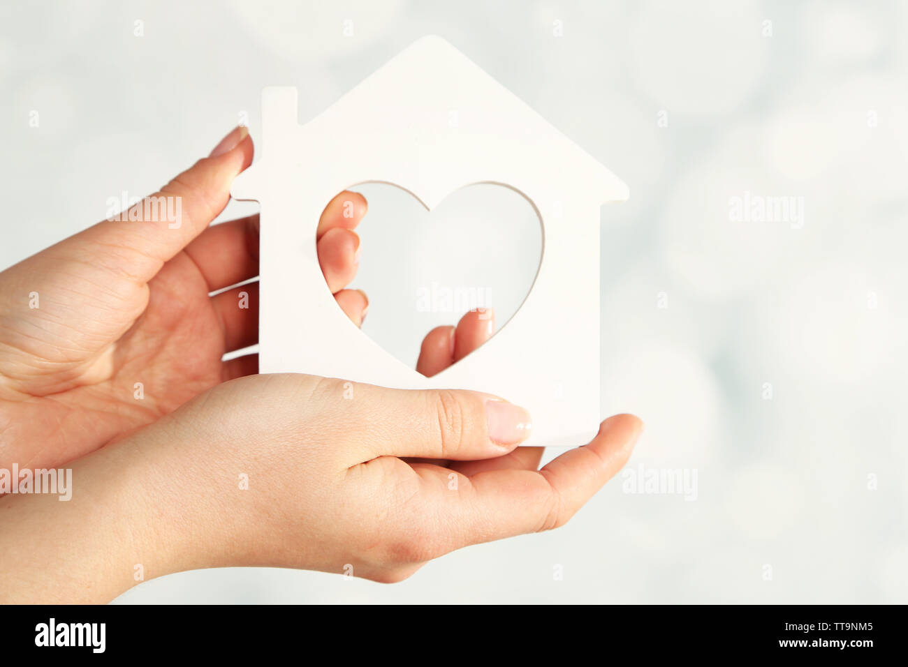 Female hands with model of house on blurred background Stock Photo - Alamy