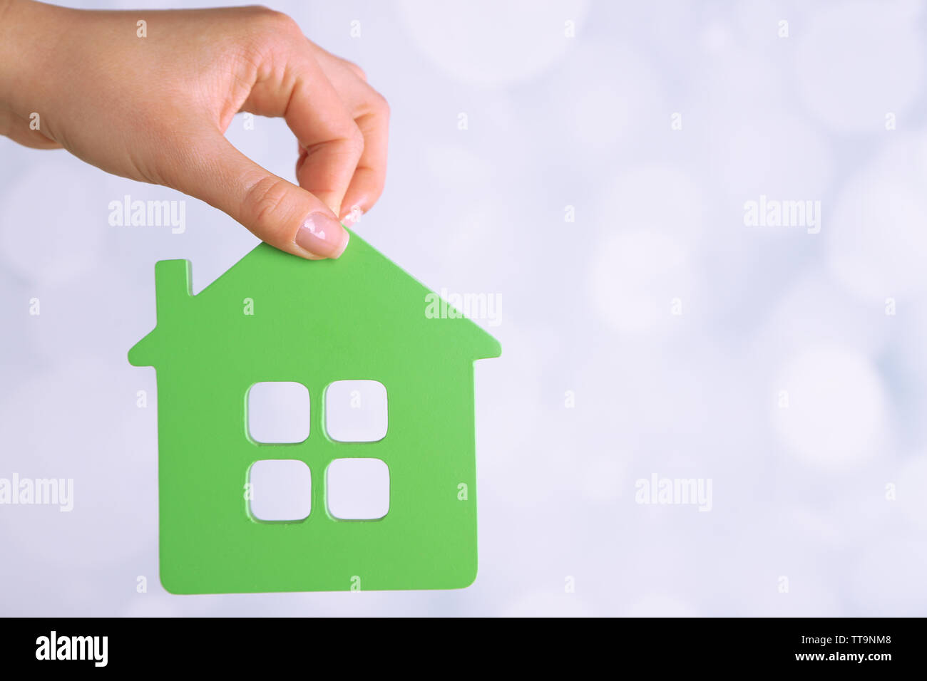 Female hand with model of house on blurred background Stock Photo - Alamy