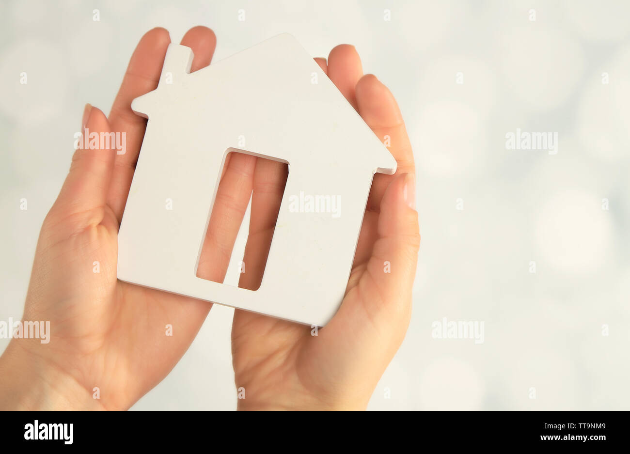Female hands with model of house on blurred background Stock Photo - Alamy