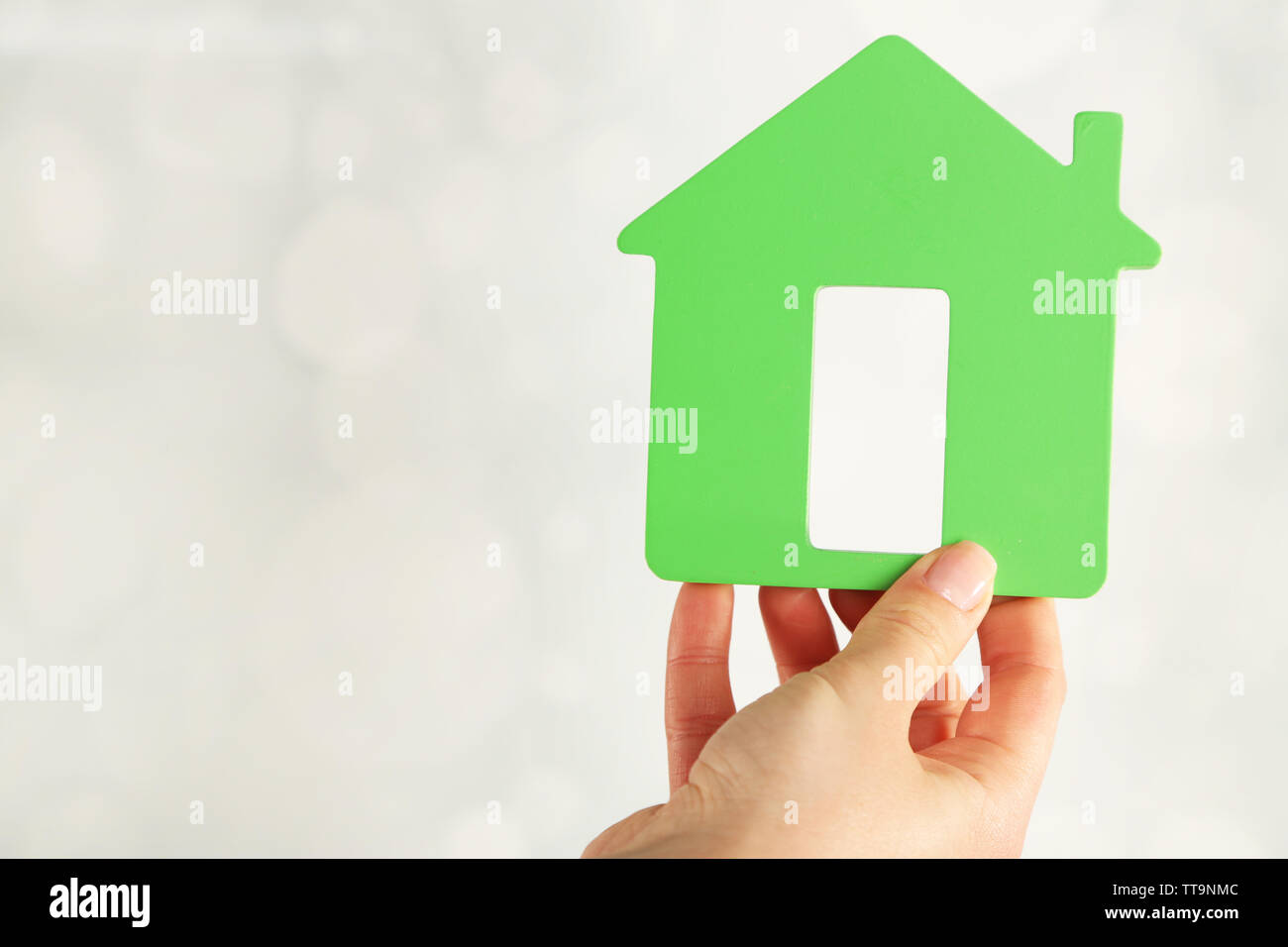Female hand with model of house on blurred background Stock Photo - Alamy