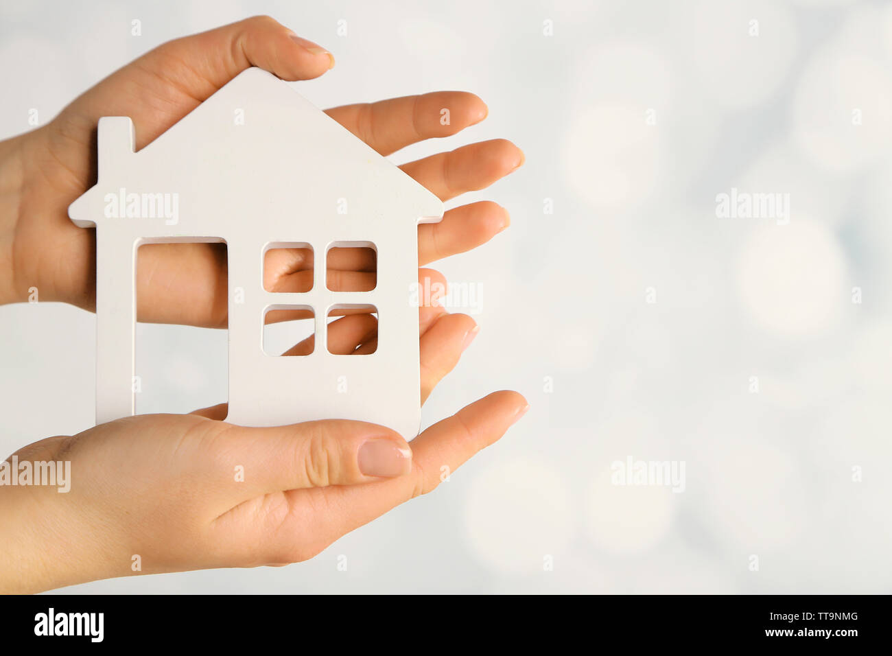 Female hands with model of house on blurred background Stock Photo - Alamy