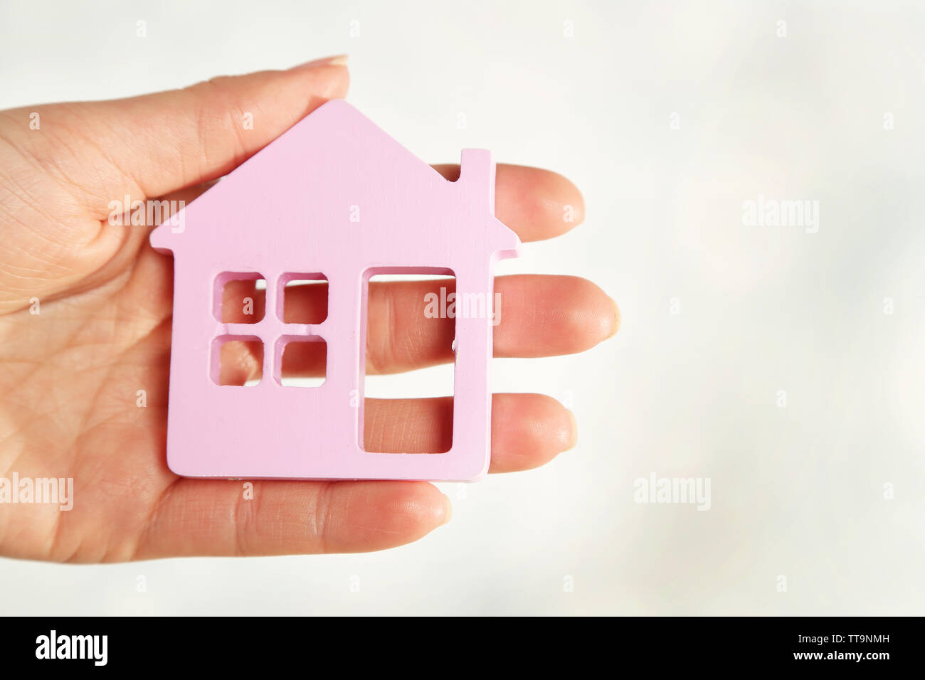 Female hand with model of house on blurred background Stock Photo - Alamy