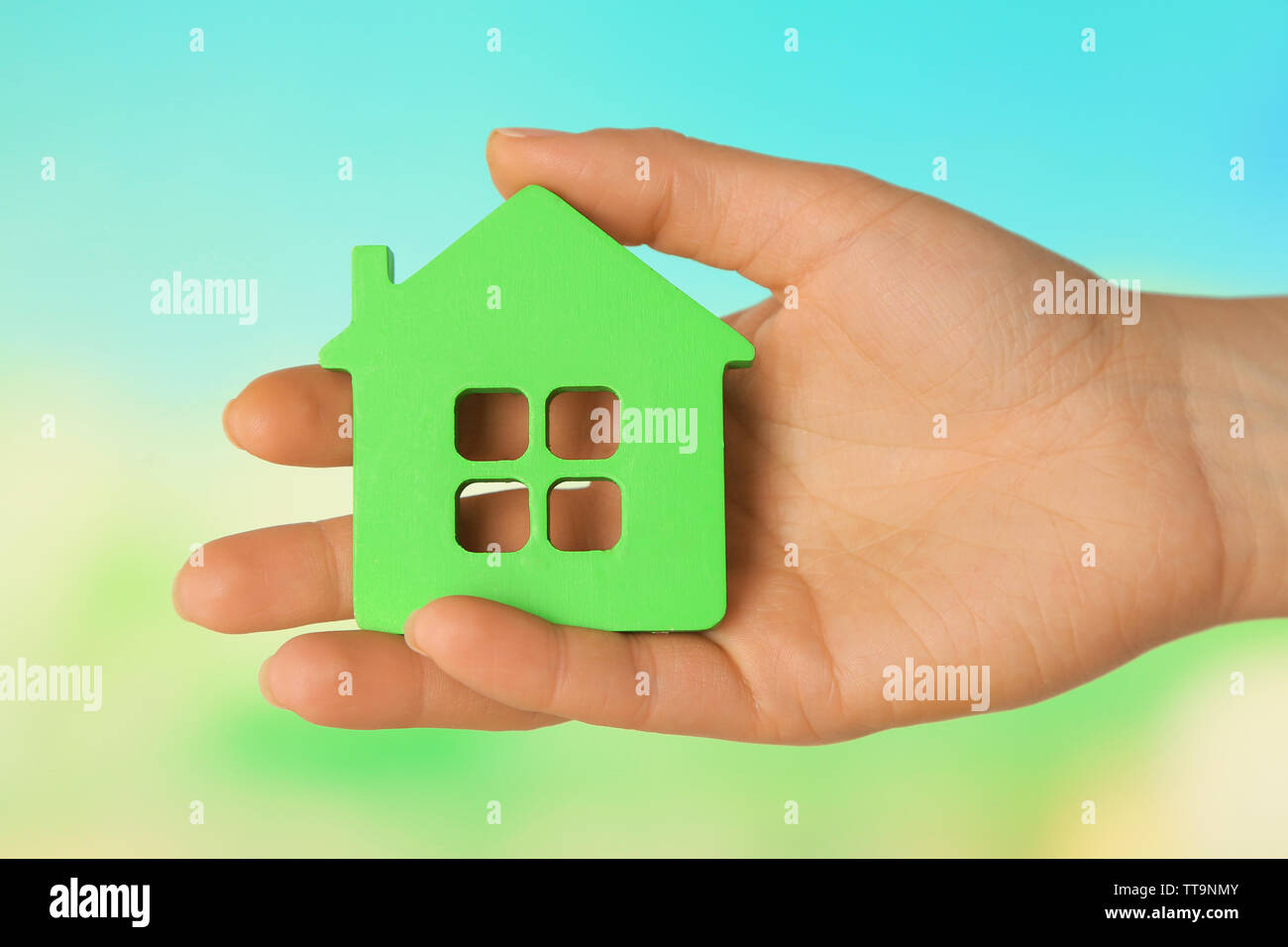 Female hand with model of house on blurred background Stock Photo - Alamy