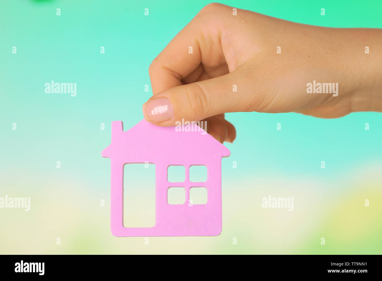 Female hand with model of house on blurred background Stock Photo - Alamy