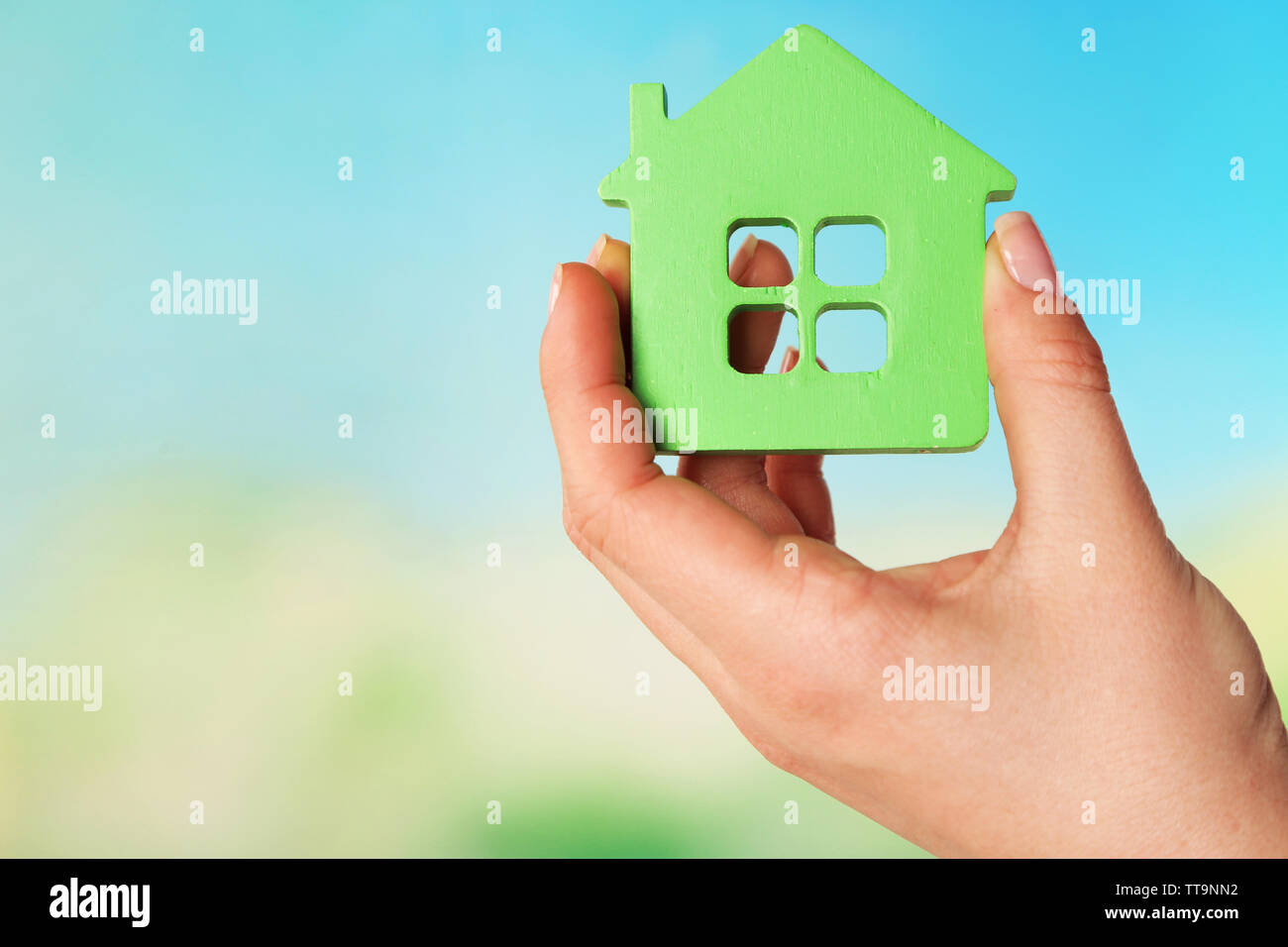 Female hand with model of house on blurred background Stock Photo - Alamy