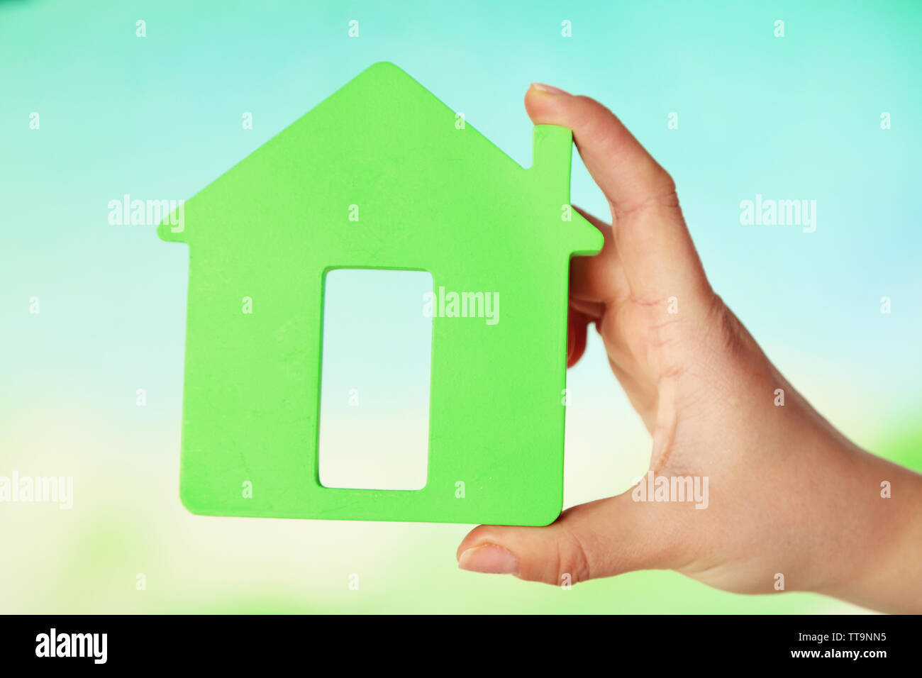 Female hand with model of house on blurred background Stock Photo - Alamy