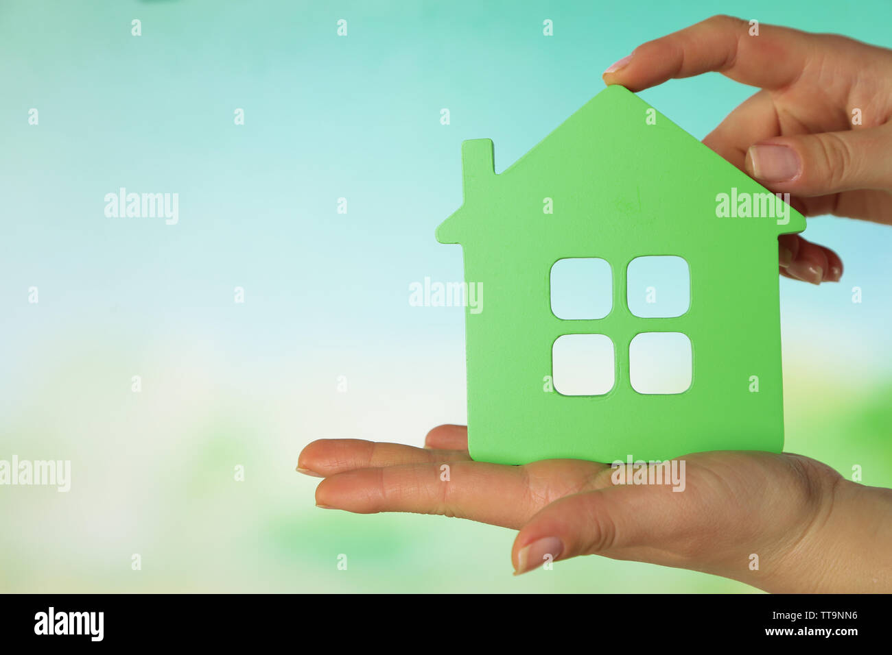 Female hands with model of house on blurred background Stock Photo - Alamy